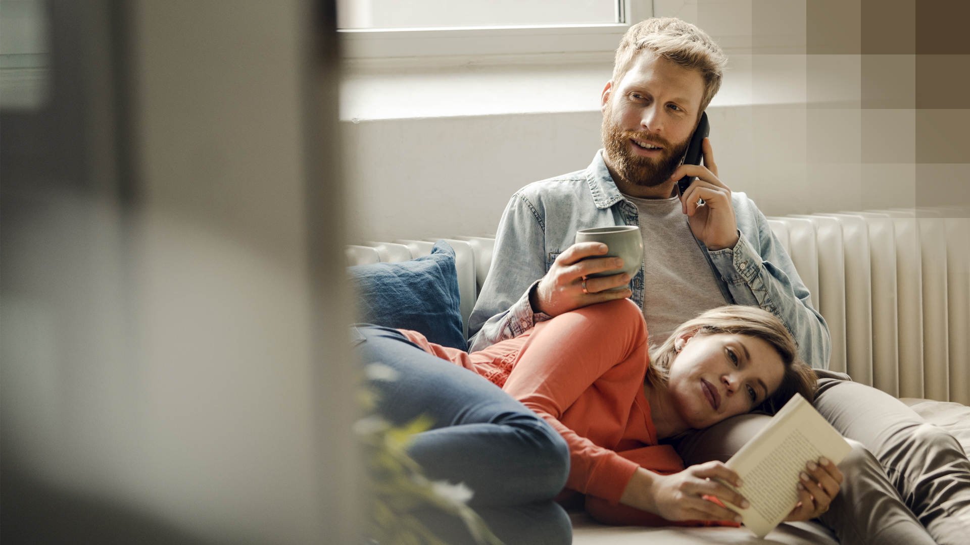 Un homme s’informe sur le modèle du médecin de famille en utilisant son téléphone, assis avec sa partenaire sur le canapé.